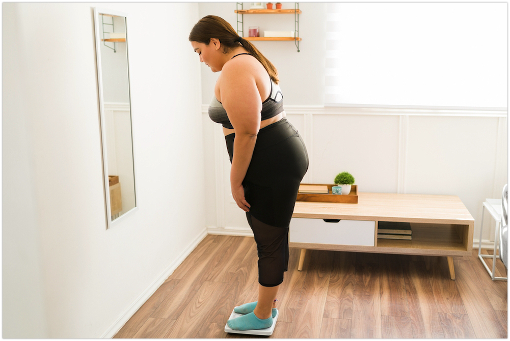 Teenager weighing self in scale in bedroom