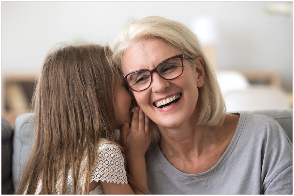 Grandaughter whispering something into her grandmother’s ear