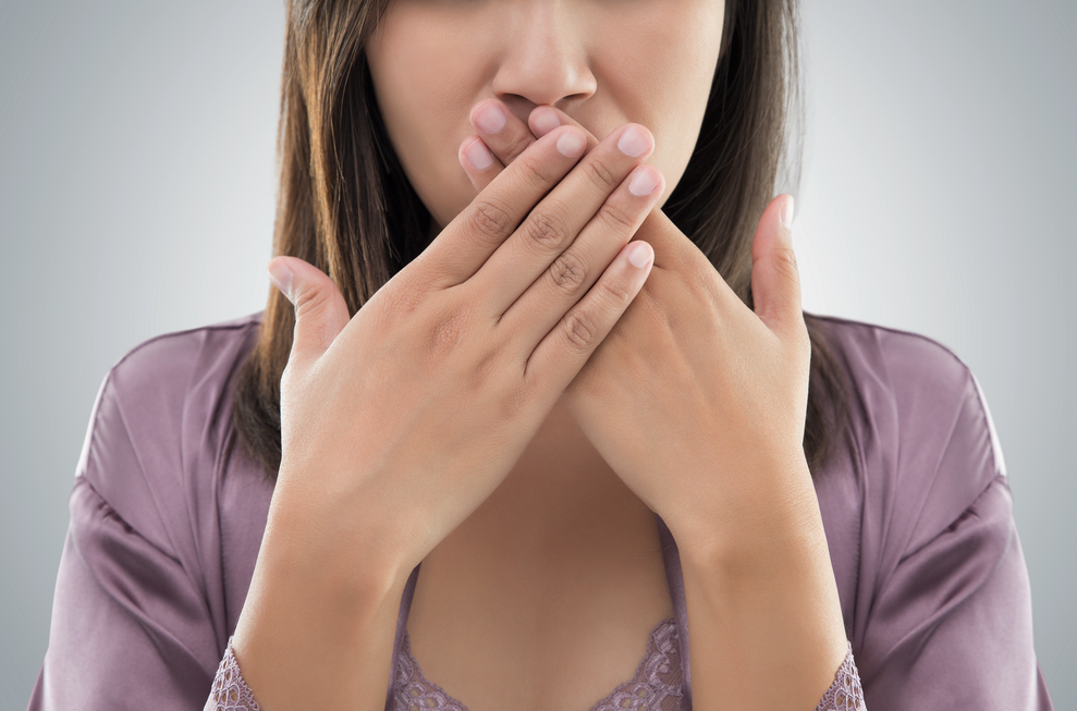 Woman with bad breath covering her mouth in embarrassment